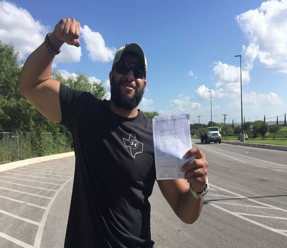 Alumno de CDL Training en Texas mostrando orgulloso el comprobante del DMV tras aprobar el examen de licencia CDL.